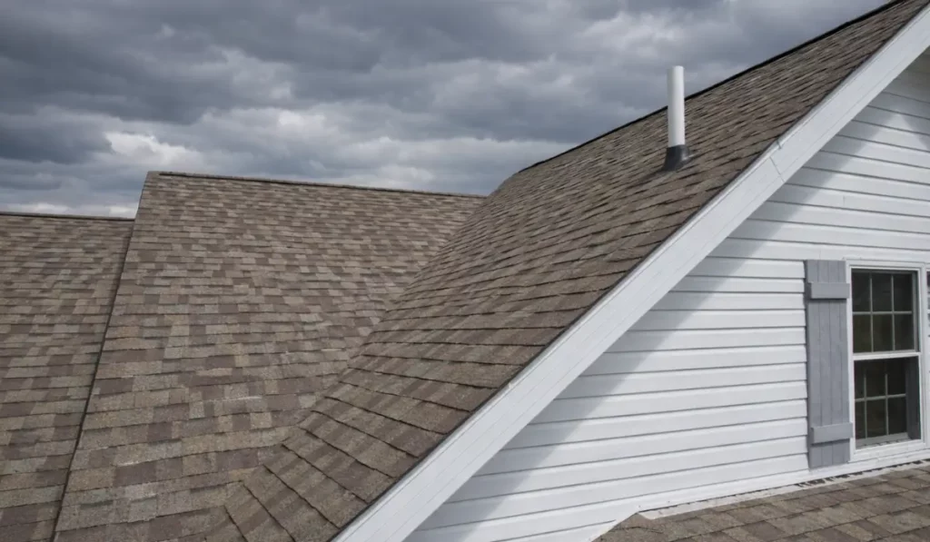 Midwest home roof and siding under dark clouds preparing for Spring Storm Season severe weather conditions.